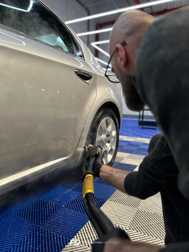 Homme nettoyant voiture au garage.
