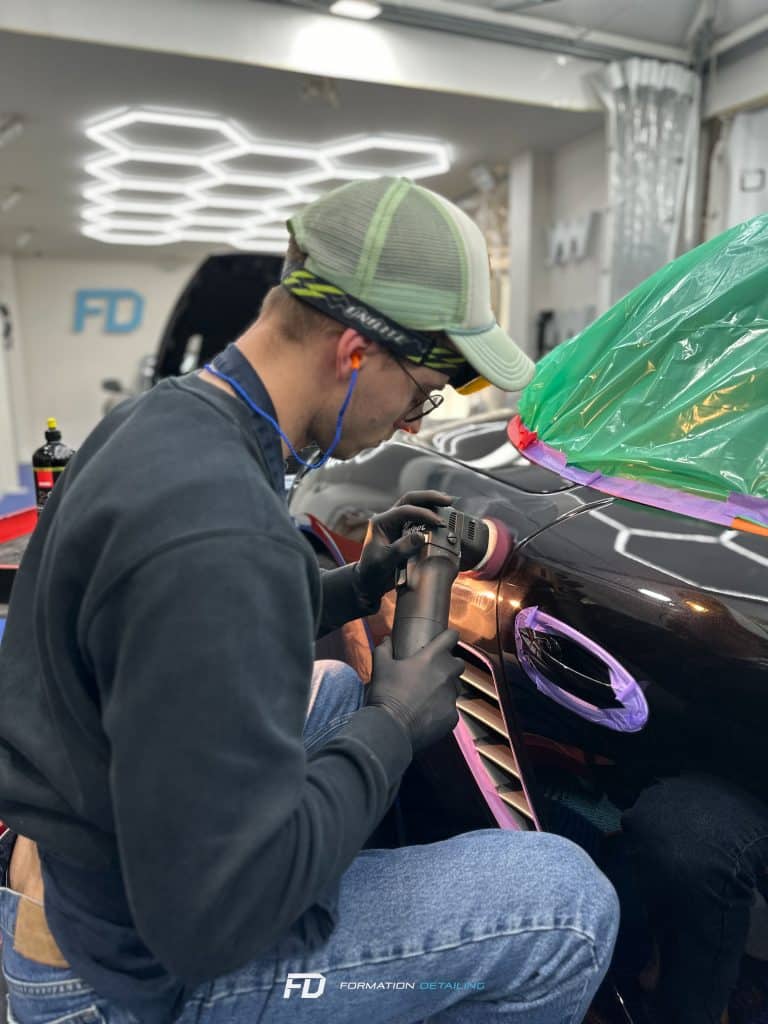 Homme polissant voiture dans atelier éclairé