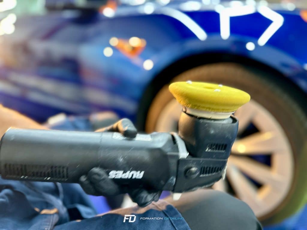 Polisseuse en action sur voiture de sport bleue